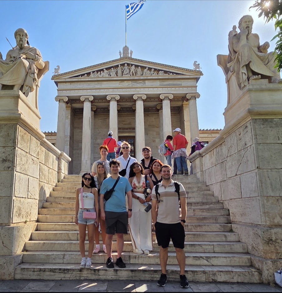 Participants on the steps of the Academy of Athens, between the statues of Plato and Socrates
